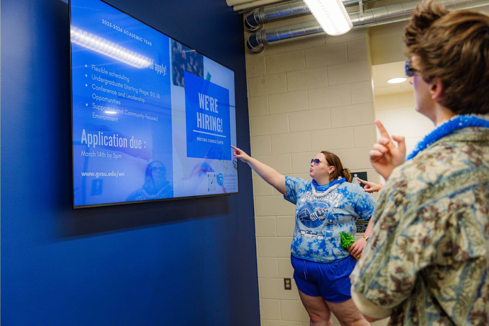 Student looking and pointing at a Laker Hub TV on campus